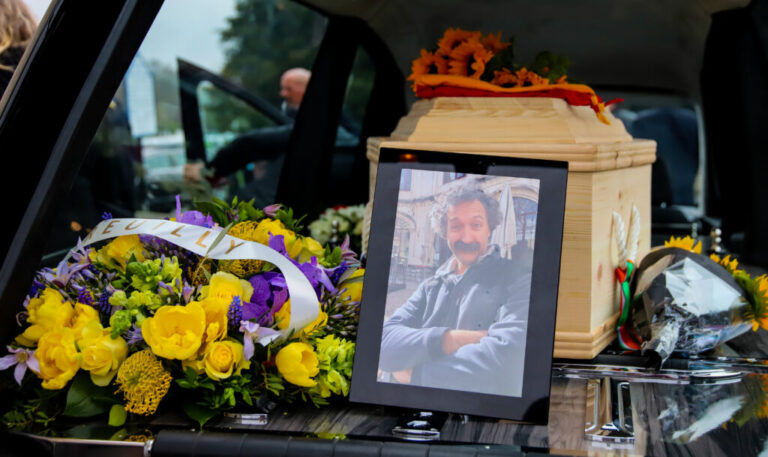 A framed photo of Pierre Zakrzewski is displayed in the hearse following his funeral in Dublin on March 29, 2022. Yellow and purple flowers are next to the photo, on the left side of the frame.