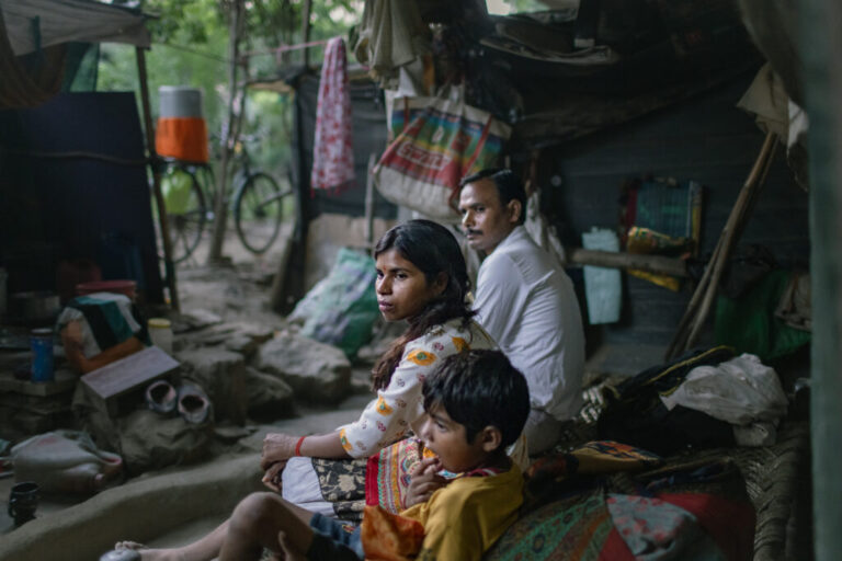 Kanchan and her son sit on his bed, next to Kamal, a relative, in the Muslim-majority neighborhood Bela Slum in New Delhi, India, October 13, 2026.