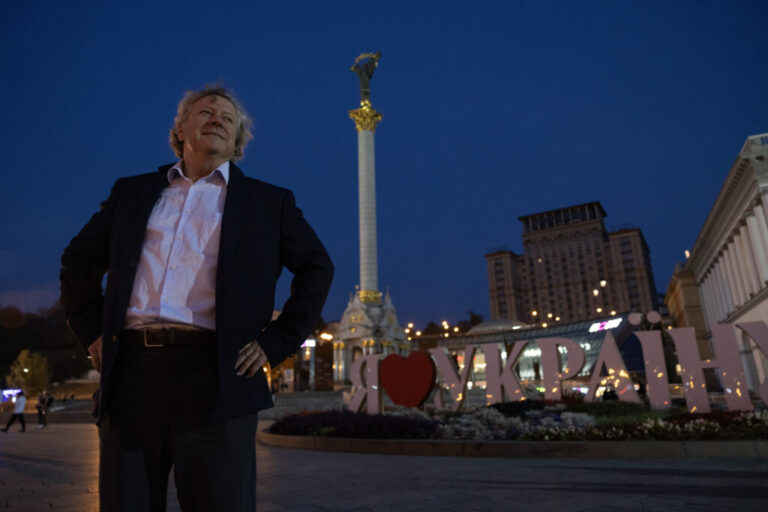 Stephen Humphreys, seen at night in Kyiv in 2024, stands in front of a sign that says in Ukrainian