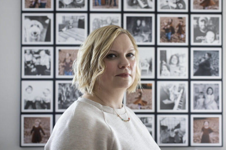 Marlatt stands in front of a grid of framed family photos.