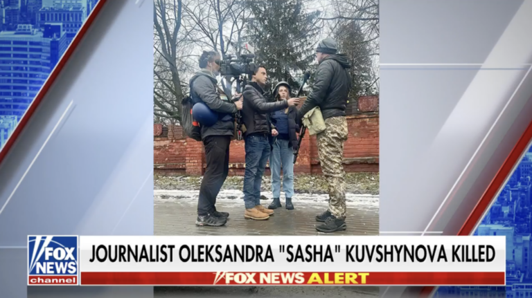 This screenshot from Fox News shows Oleksandra Kuvshynova standing outdoors with two other members of a news crew — one holding a microphone and the other holding a TV camera — as they interview a man wearing camouflage pants and carrying a firearm. The text at the bottom of the screen says: