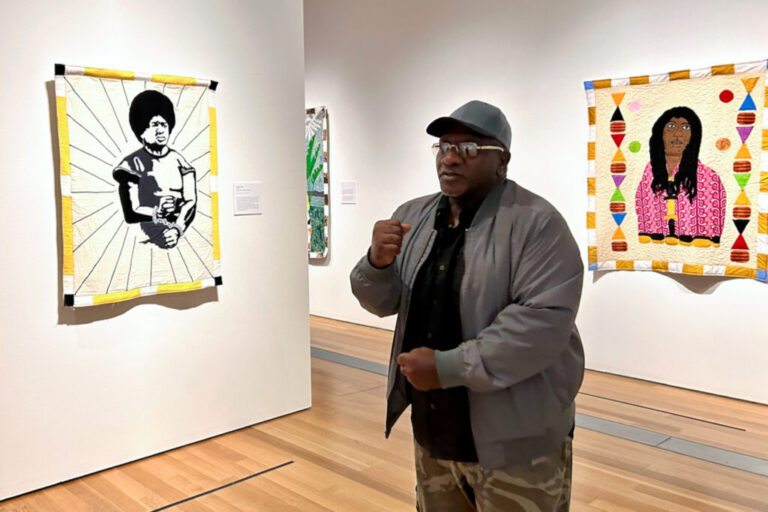 Artist Gary Tyler stands before his quilt,