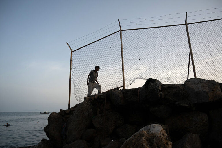 A migrant walks along a rocky shoreline near the border with Morocco after swimming towards Spain's North African enclave of Ceuta on July 31, 2026.