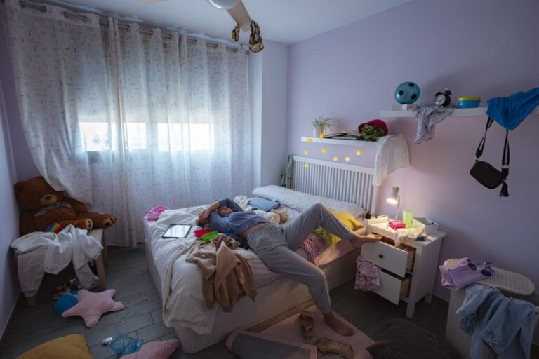 Lazy teenager laying in bed in her messy room