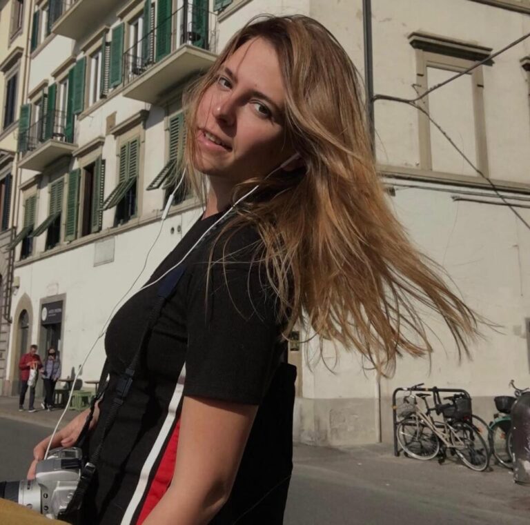 Oleksandra Kuvshynova stands outside a multistory building with green wooden shutters while visiting Italy in 2021.