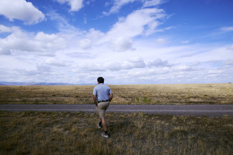Louie Delaware walks through an open area near his rebuilt home in Louisville, Colo. The landscape includes areas where homes destroyed in the Marshall Fire have not been rebuilt. The costs of adapting to climate-related impacts are part of Boulder County’s claims against ExxonMobil and Suncor Energy. (Jimena Peck for NPR)