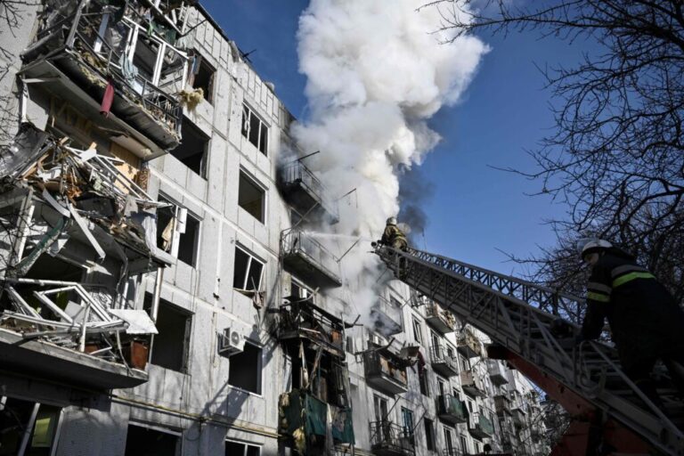Firefighters climbing on a firefighting crane work to put out a fire at a bombed multistory building in Chuhuiv, Ukraine, on February 24, 2022.
