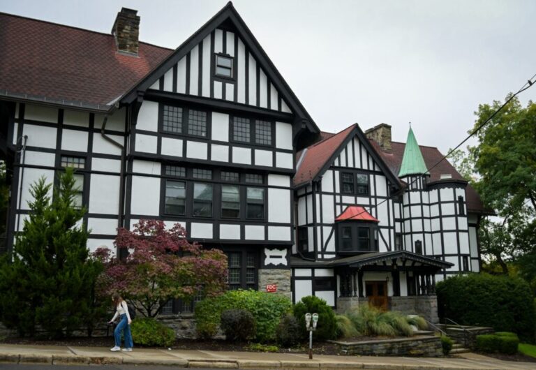 A woman walks by a large English Tudor-style building that is the Chi Phi fraternity house at Cornell University in Ithaca, N.Y., on Monday.